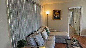 A living room with a sofa, a floor lamp, a painting, and a potted plant. - Beautiful 3-bedroom house with big yard (Duarte)