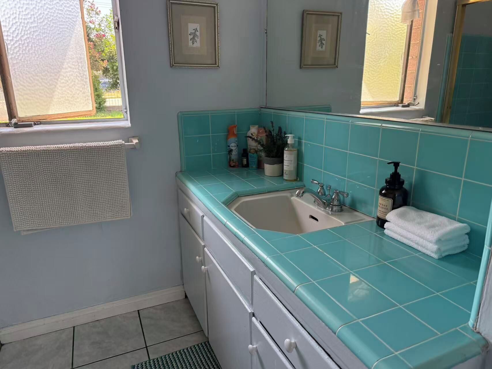 A bathroom with a sink, mirror, and a window.
