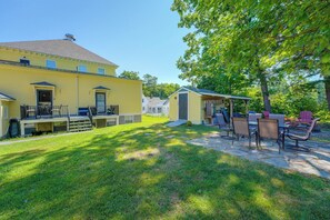 Ein gelbes Gebäude mit einer überdachten Terrasse, Sitzgelegenheiten im Freien und einem gepflegten Rasen.