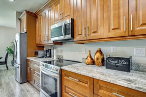 A modern kitchen with wooden cabinets, stainless steel appliances, and a marble countertop. - 6 Mi to Port Charlotte Beach Park! Family Getaway (Port Charlotte)