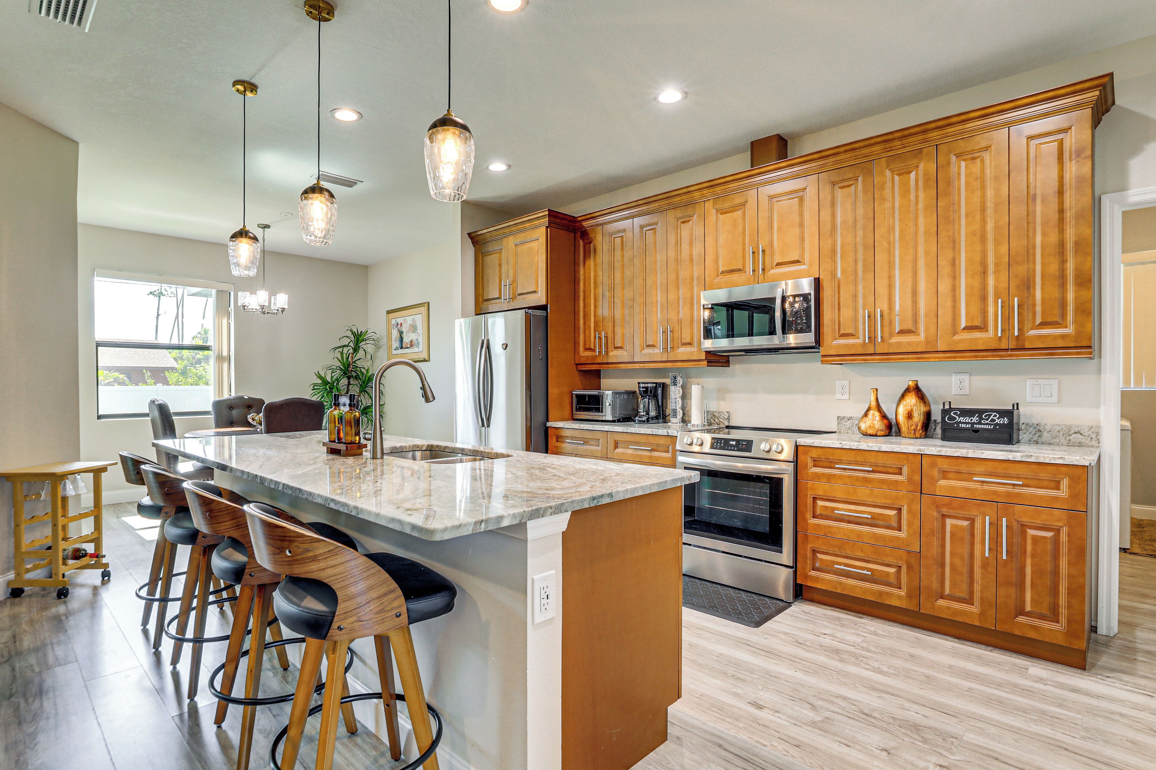 A modern kitchen with wooden cabinets, stainless steel appliances, and a central island with bar stools.