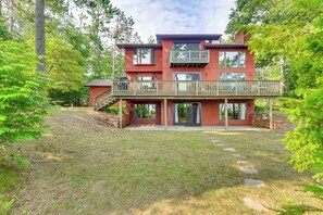 A two-story house with a deck and a covered patio area. - Private Beach on Lake Huron! Group Retreat w/ Deck (Cheboygan)