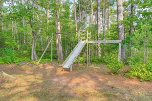 A playground with a slide and climbing structures in a wooded area. - Private Beach on Lake Huron! Group Retreat w/ Deck (Cheboygan)