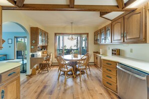 A spacious kitchen with wooden cabinets, a dining table, and chairs. - Private Beach on Lake Huron! Group Retreat w/ Deck (Cheboygan)