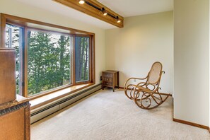 A room with a large window, a rocking chair, and a small wooden cabinet. - Private Beach on Lake Huron! Group Retreat w/ Deck (Cheboygan)