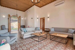 A spacious living room with a patterned floor, two sofas, a coffee table, and a stone wall.
