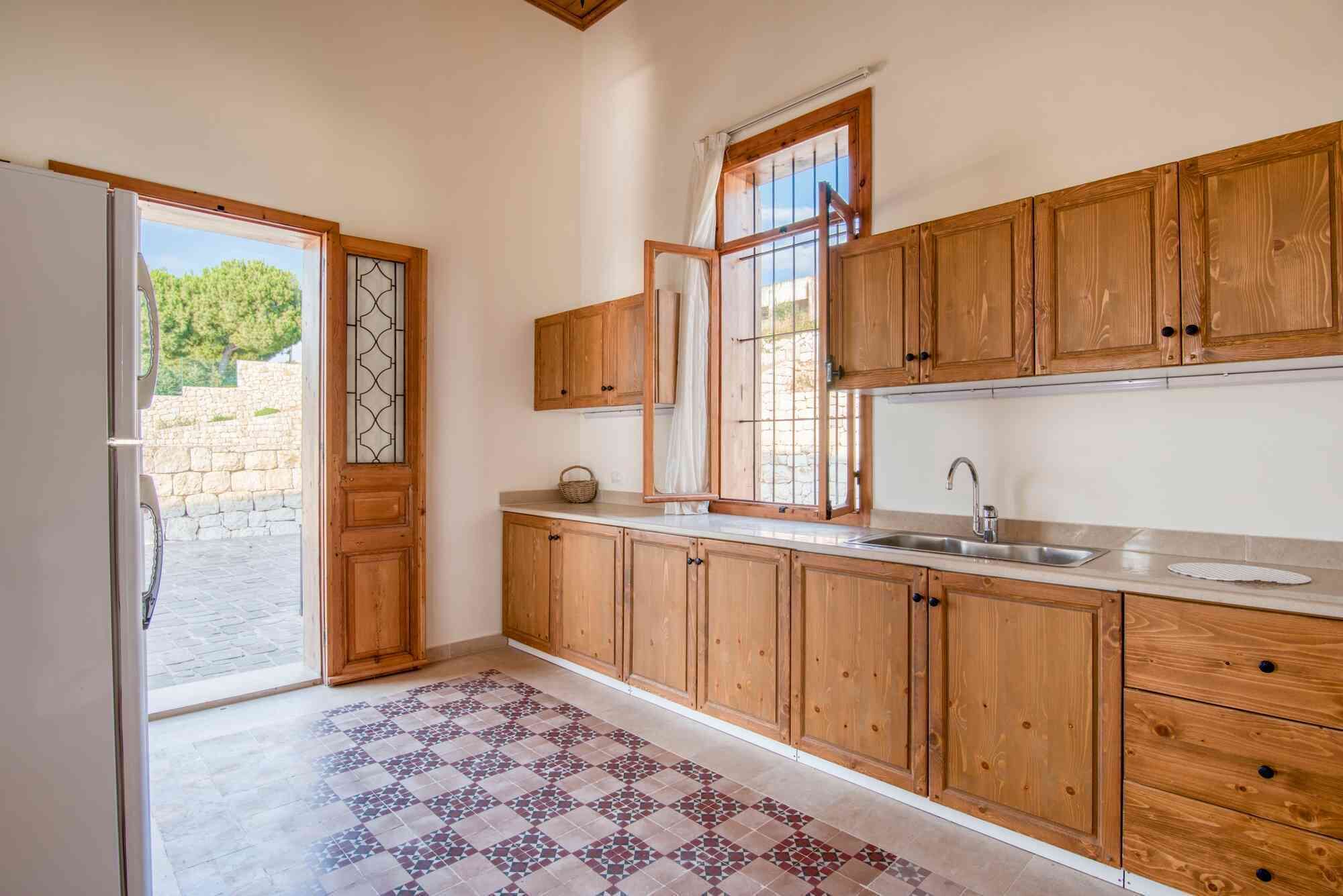 A kitchen with wooden cabinets, a sink, and a patterned floor.