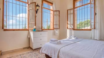 A hotel room with a bed, a dresser, a nightstand, and a window with curtains.