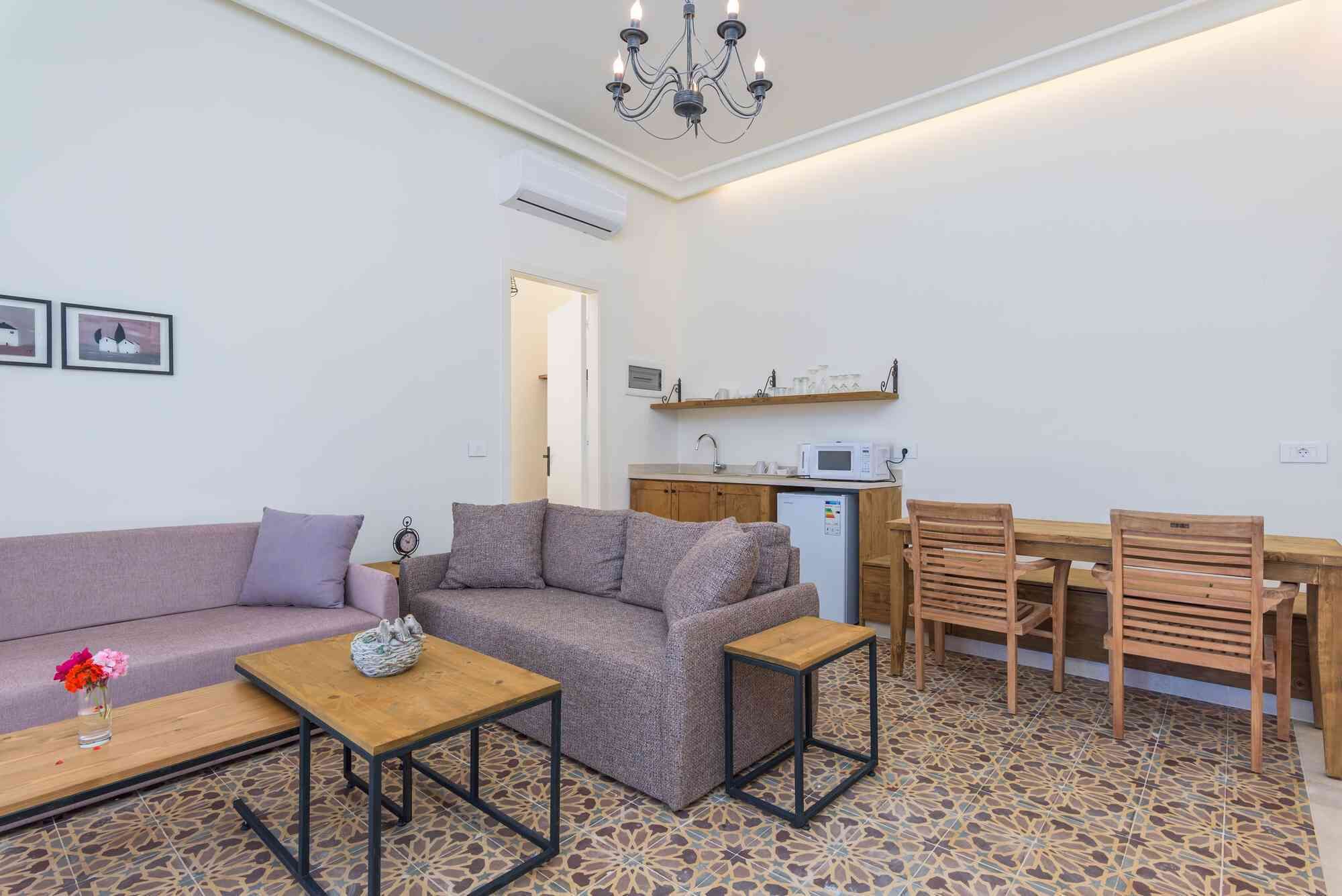 A compact living space with a sofa, a small table, a dining area with chairs, and a kitchenette.
