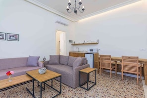 A compact living space with a sofa, a small table, a dining area with chairs, and a kitchenette.