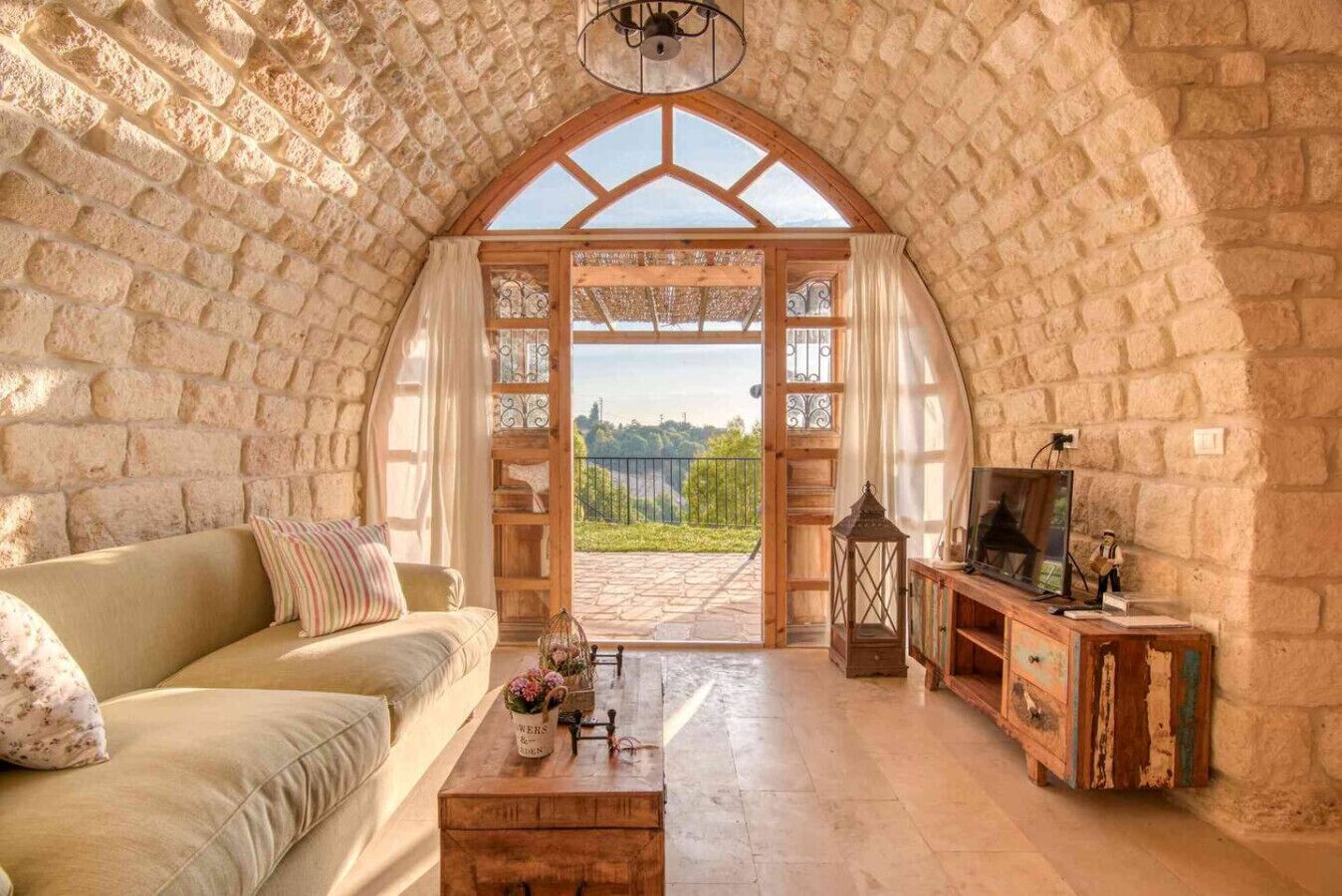 A cozy room with a stone wall, a wooden sofa, a coffee table, and a TV on a wooden cabinet.