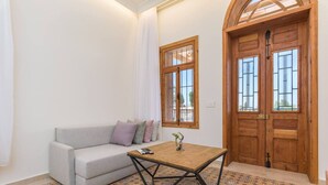 A room with a sofa, a small table, and a wooden door with glass panels.