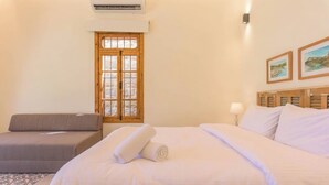Een hotelkamer met een bed, een bank, een raam met uitzicht en een wandairconditioner.