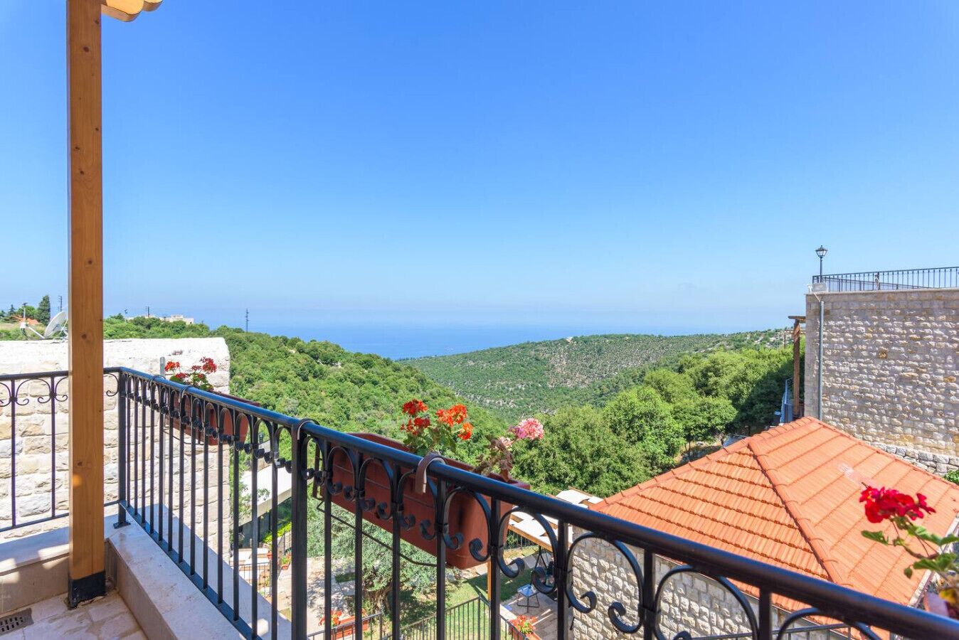 A balcony with a stone wall and a metal railing overlooking a mountainous landscape.