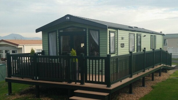 A single-story mobile home with a front porch and a small deck. - Hafan y Mor Haven - Holiday Accommodation 7021 (Pwllheli)