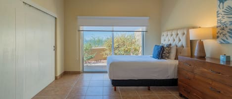 Un dormitorio con cama, cómoda y ventana con vista a árboles.