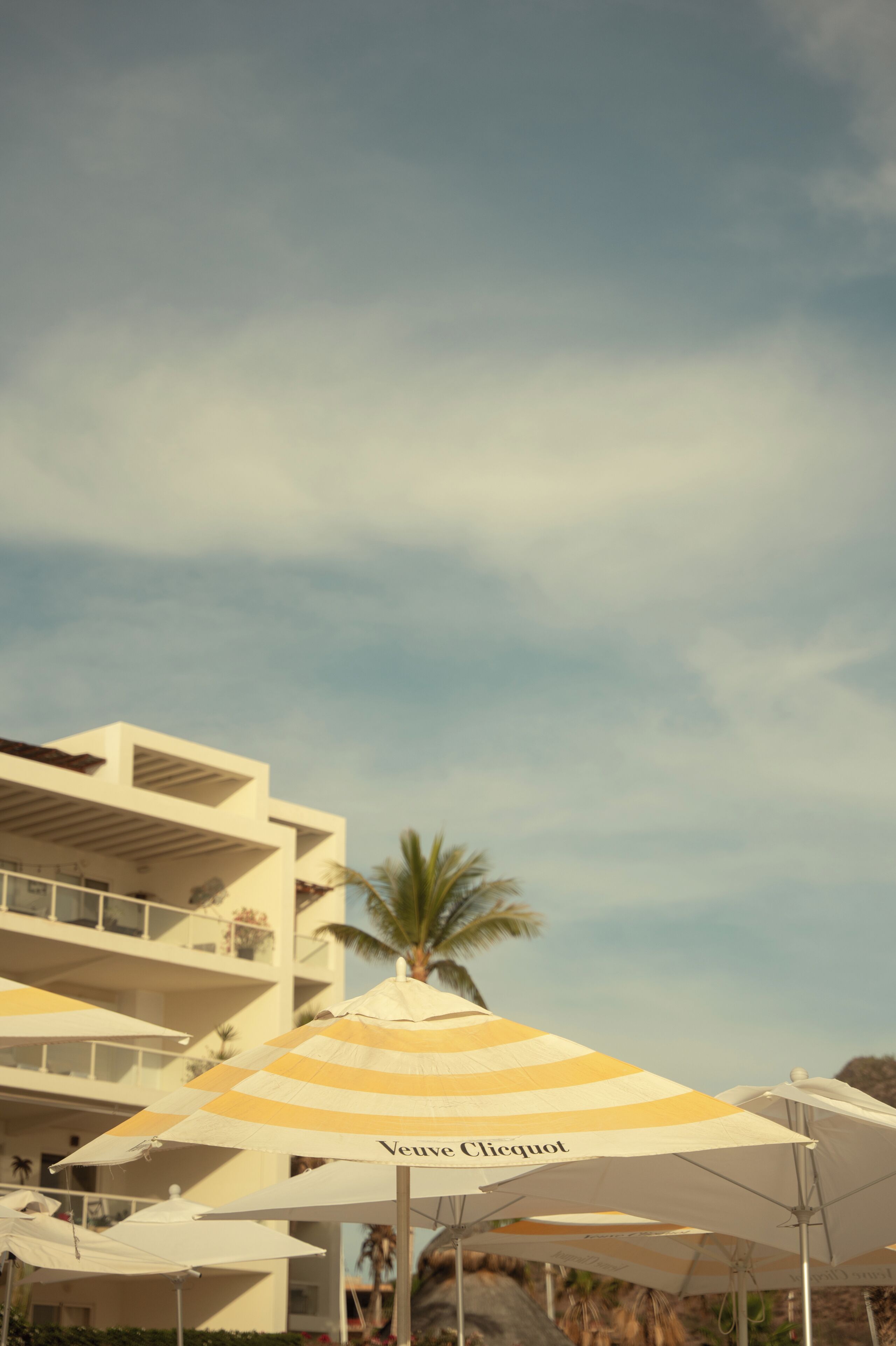 A hotel with multiple white umbrellas, one with 'Veuve Clicquot' branding.