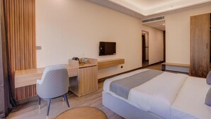 Una habitación de hotel moderna con cama, escritorio, silla, televisor y ventilador de techo.