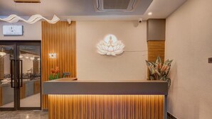 Un mostrador de recepción con detalles de madera y una lámpara con forma de flor de loto en el techo.