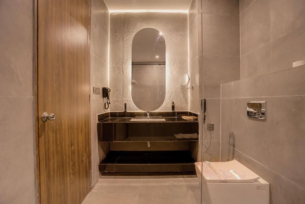Een moderne badkamer met een houten deur, een grote spiegel, een wastafel en een douchehoek.