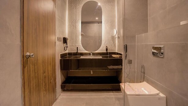 Een moderne badkamer met een houten deur, een grote spiegel, een wastafel en een douchehoek.