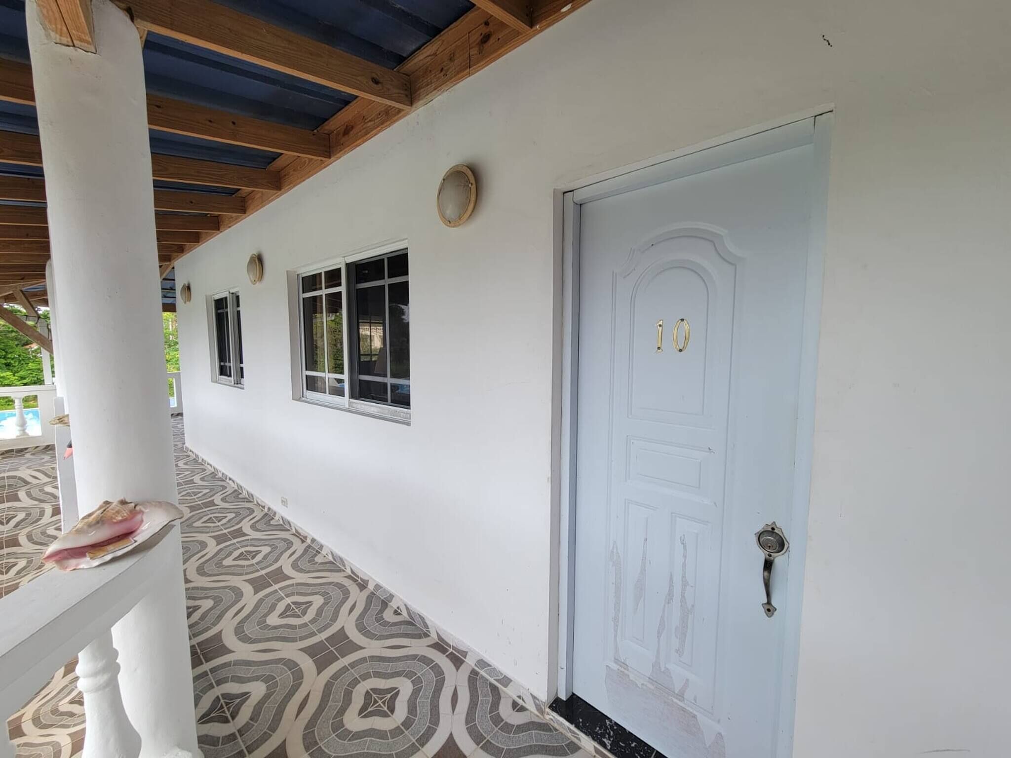 A corridor with a white door marked with the number 10, a patterned floor, and a white column.