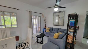 Ein Wohnzimmer mit einer Couch, einem Hocker und einem Deckenventilator.