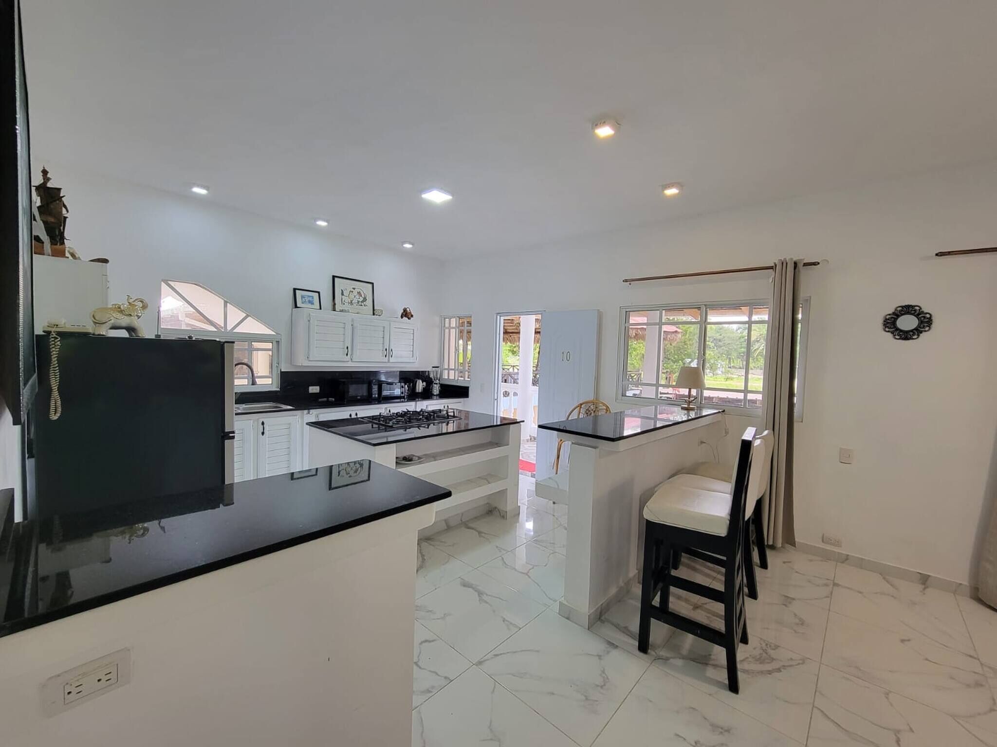 A modern kitchen with a central island, white cabinetry, and a dining area with a chair.
