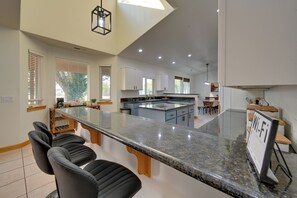 Eine moderne Küche mit einer großen Kochinsel, Barhocker und einem Essbereich mit Tisch und Stühlen.
