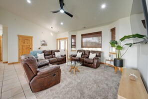A spacious living room with leather sofas, a glass coffee table, and a ceiling fan. - Kennewick Hideaway: Yard, Deck, 2 Living Rooms (Kennewick)