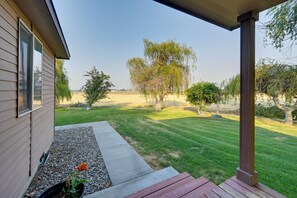 Ein Haus mit Veranda, Rasen und Bäumen im Hintergrund.