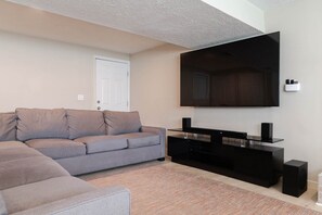 A living room with a sectional sofa, a flat-screen TV, and a black entertainment unit. - Hot Tub+Game Room, 8 Ski resorts + SLC | Sleeps 14 (Centerville)