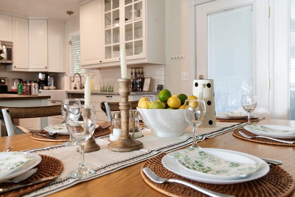 A dining table set with plates, glasses, and a centerpiece of lemons and a candle.