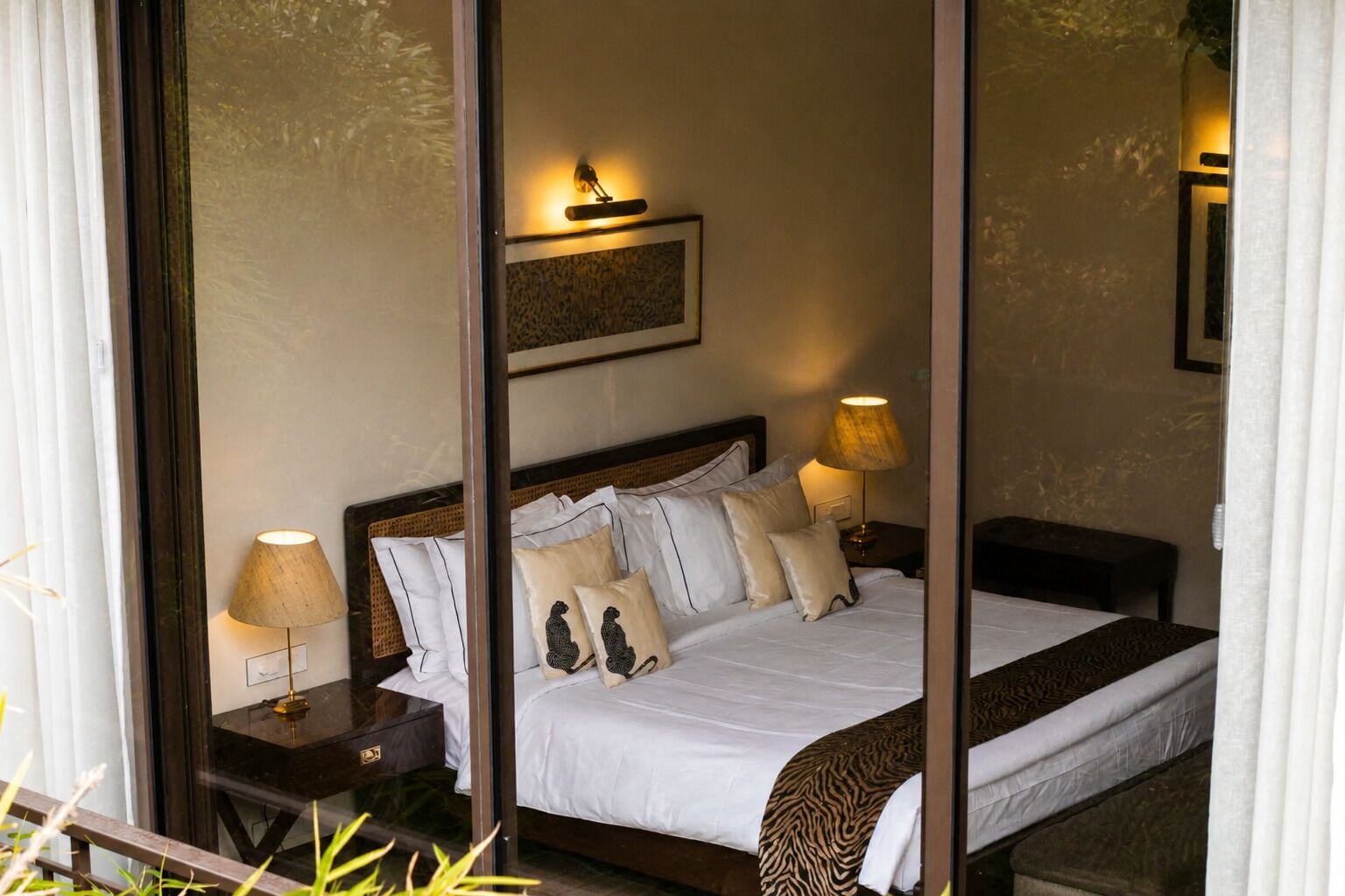 A hotel room with a bed, two bedside tables with lamps, a headboard, and a wall-mounted light fixture.