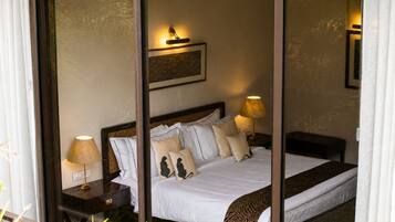A hotel room with a bed, two bedside tables with lamps, a headboard, and a wall-mounted light fixture.