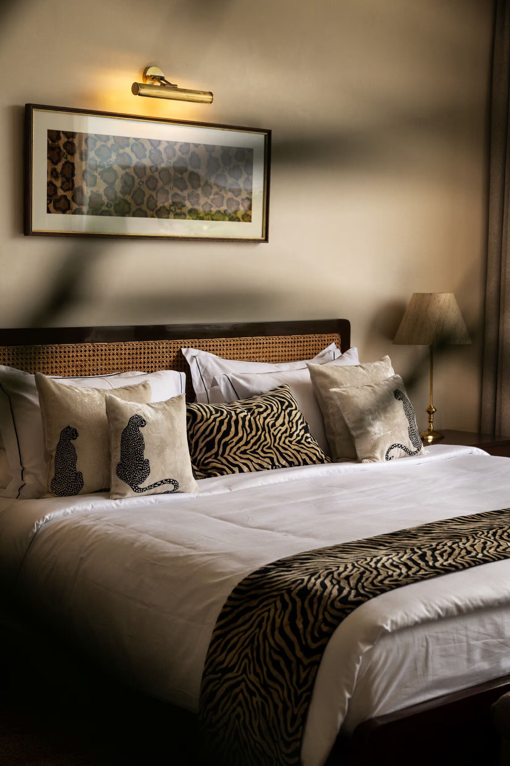 A neatly made bed with a zebra-patterned throw, a headboard with a woven design, and a framed picture above the bed.