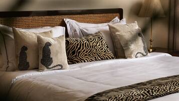 A neatly made bed with a zebra-patterned throw, a headboard with a woven design, and a framed picture above the bed.