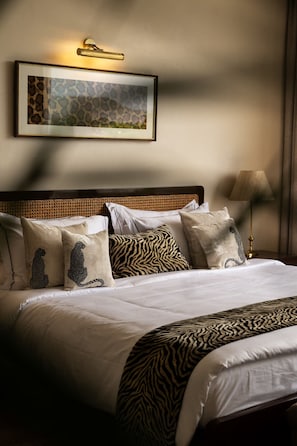 A neatly made bed with a zebra-patterned throw, a headboard with a woven design, and a framed picture above the bed.