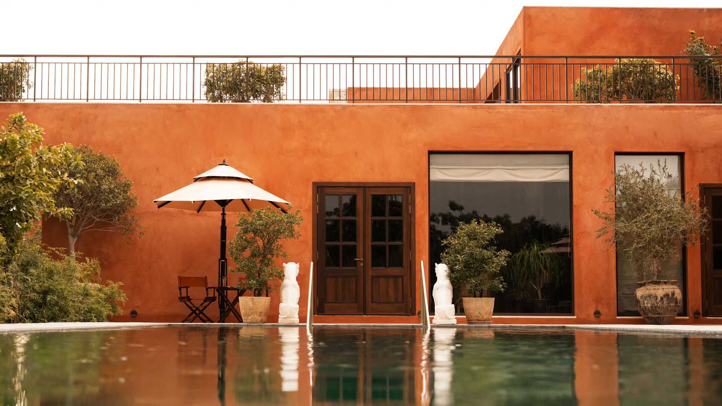 A modern building with a swimming pool, outdoor seating, and a large window.