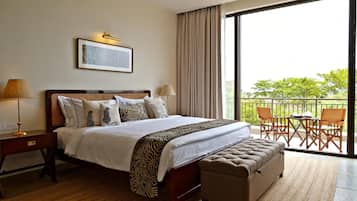 A hotel room with a large bed, a desk, a chair, and a balcony with outdoor furniture.