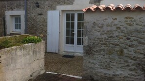 A stone building with a tiled roof, a white door, and a small window.