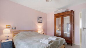 Un dormitorio con una cama, lámparas de noche, un espejo y un reloj de pared.