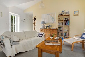 A cozy living room with a sofa, a wooden coffee table, a bookshelf, and a map on the wall.