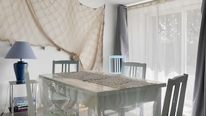 Comedor con una mesa preparada para cuatro personas, una lámpara y una silla.