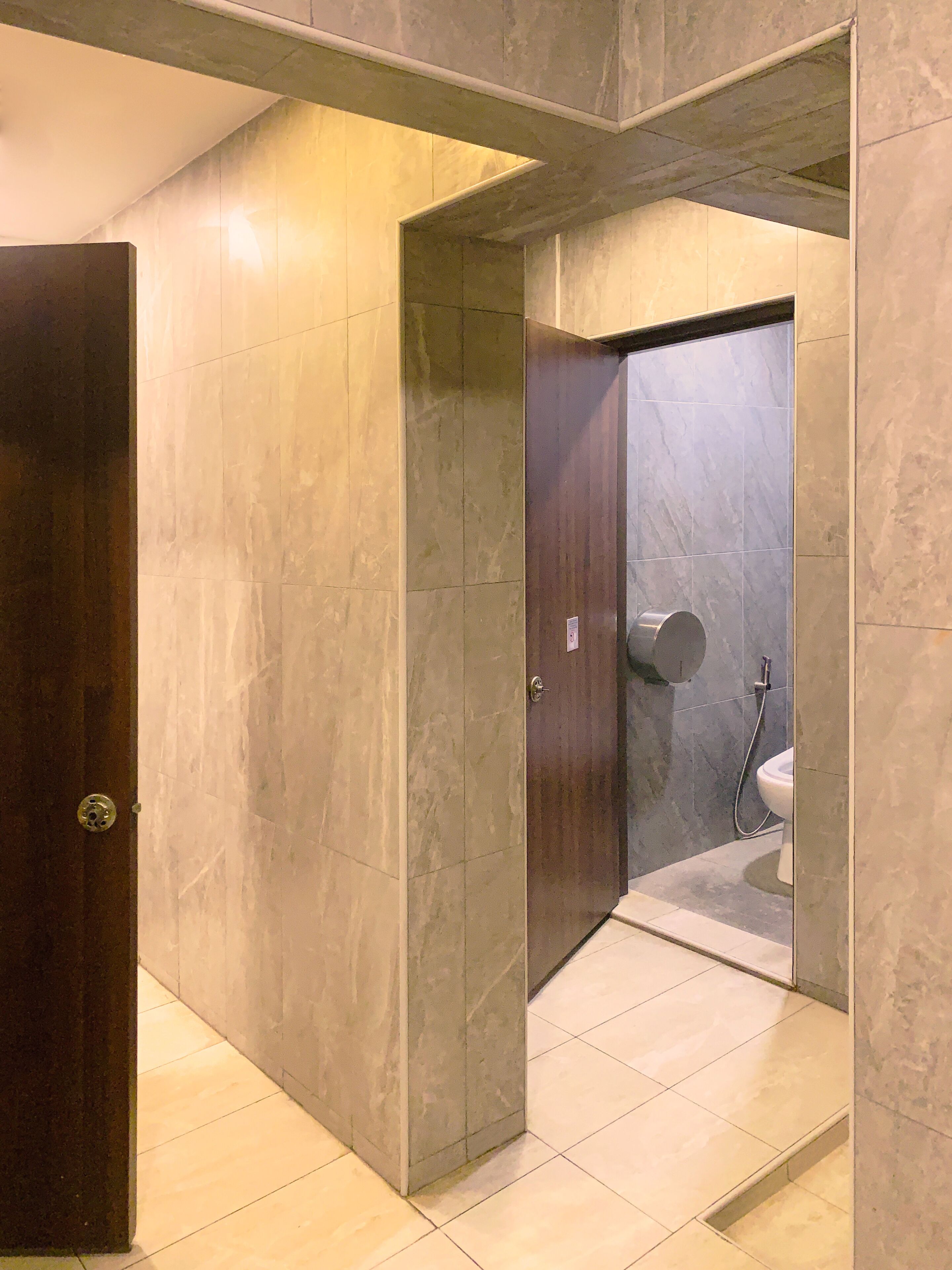 A bathroom with a toilet, shower, and a door leading to another room.
