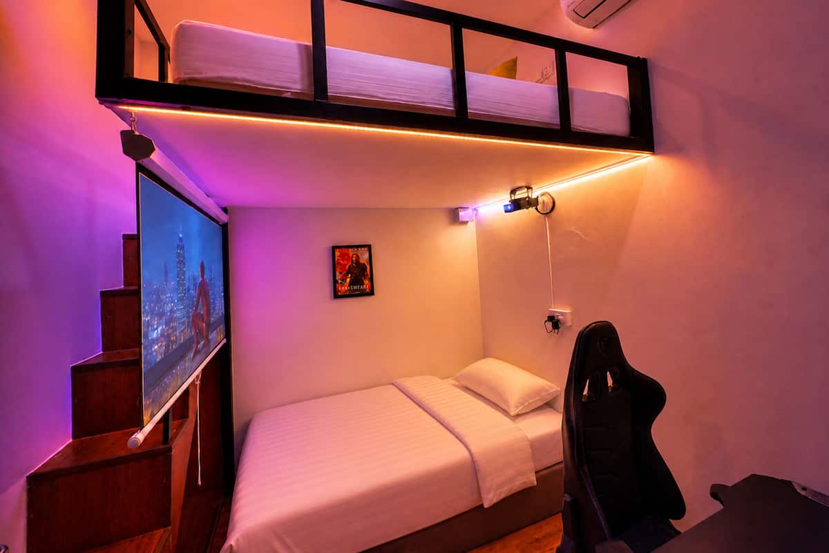 Una habitación pequeña con una cama litera, un escritorio y un televisor fijado a la pared.