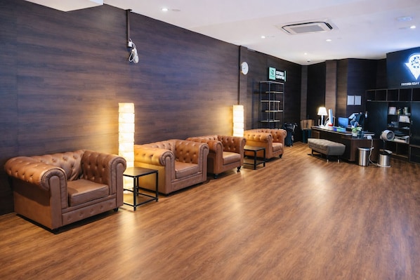 A reception area with a dark wood floor, leather sofas, a reception desk, and a clock on the wall.