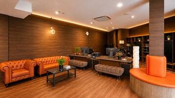 A modern lobby with a sofa, ottoman, and a curved seating area.