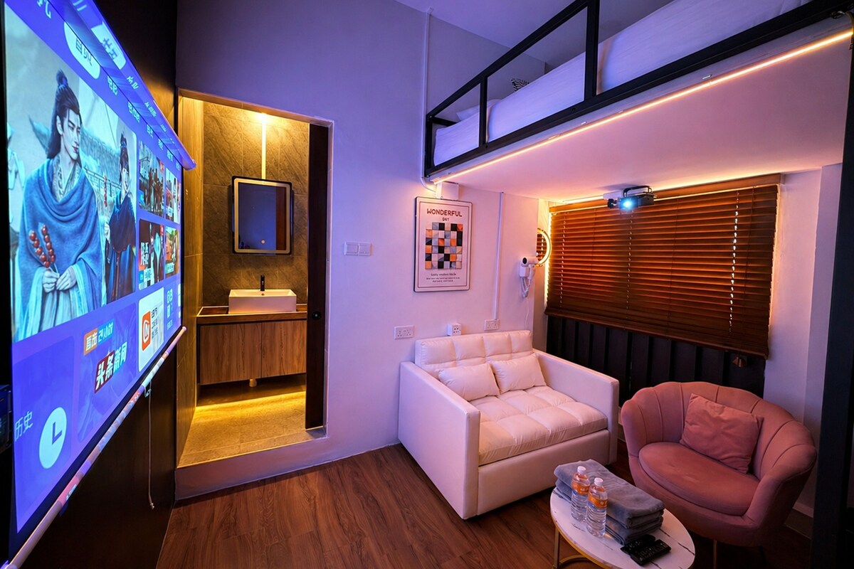 Una sala moderna con un sofá, un sillón y un televisor mostrando un programa.