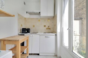 Eine kleine Küche mit weißer Arbeitsplatte, einer Kaffeemaschine und einem Spülbecken.
